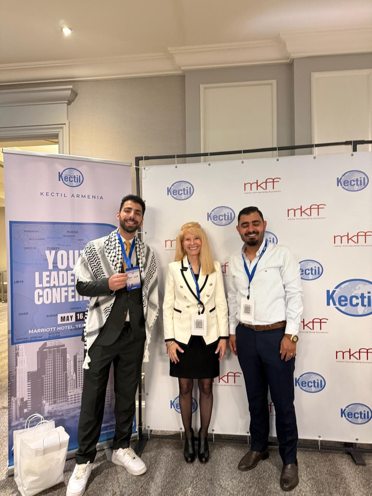 Three Kectil participants standing in front of an Armenia conference backdrop.